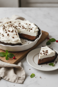 Finished easy chocolate pudding pie on a white ceramic pie plate, one neat slice removed and plated beside it